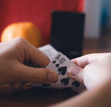Hands holding Ace and 10 of spades playing cards in a blackjack hand